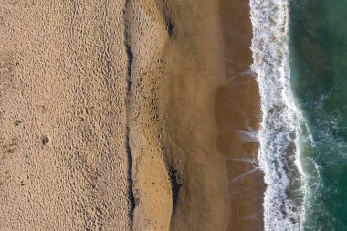 Uzaktan kumlu bir sahilin havadan görünüşü. Ayak sesleri ve drone 'larla deniz dalgaları.