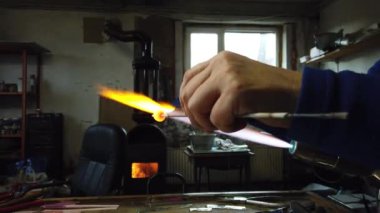  Sanatçı ellerine yaklaş lamba çalışma tekniğiyle cam kolye yap. Gaz ocağı kullanarak cam ve alevi şekillendirmek.