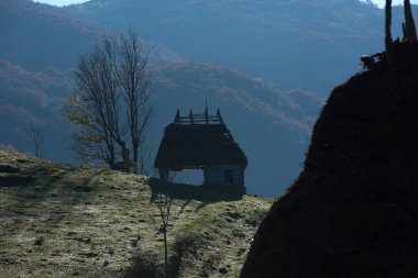 Sonbahar kır manzarası, ahşap evler, güneş doğarken sazdan çatı.