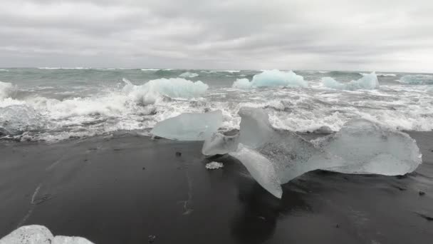 冰岛黑色火山灰 钻石海滩海浪上融化冰晶冰山的慢镜头 — 图库视频影像