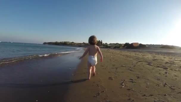 海の波を通してサンディビーチで走るナッピングでトッドラーの赤ん坊ガール — ストック動画
