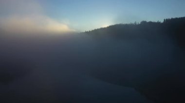 Gün doğumunda sisli dağın yavaş çekim görüntüsü. Bulutların üzerinde İHA ile uçuyor