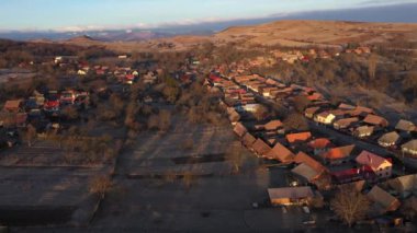  Sabahın erken saatlerinde köy evlerinin üzerinde gün doğumu ışıkları, hava aracı manzarası.