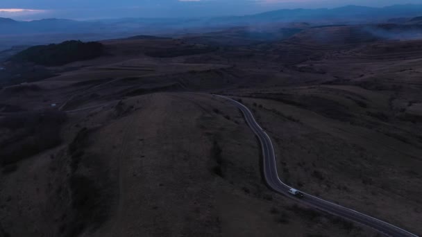 Αυτοκίνητο Που Περνά Ένα Ορεινό Δρόμο Στο Σούρουπο Φώτα Κεραία — Αρχείο Βίντεο