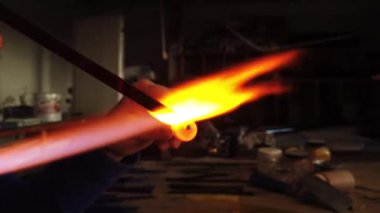   Bir atölyedeki gaz lambasının üzerinde duran cam boncuğu şekillendiren ellerin yakın plan çekimi. Cam işi mücevherler.