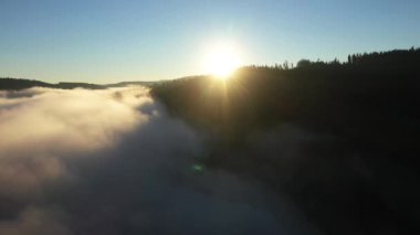 Gün doğumunda sisli dağın yavaş çekim görüntüsü. Bulutların üzerinde İHA ile uçuyor