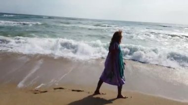 Kumsalda yürüyen seksi sarışın kadın.
