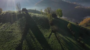 Dağ kulübesinin drone görüntüsü. Sonbaharda, sazdan çatısı olan terk edilmiş evlerle birlikte havanın sisli manzarası. Transilvanya, Romanya