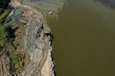 Nehir kumu ve çakıl taşlarının insansız hava aracıyla nehir kıyısında kazıcıyla yasadışı şekilde kullanılmasının hava görüntüsü