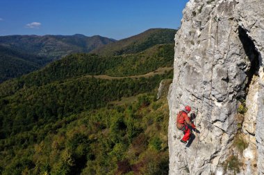 Aerial view of mountain rescuer doing rescue operations hanging on a rope clipart