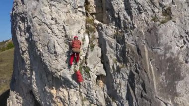 İpe asılı kurtarma operasyonları yapan bir dağcının hava görüntüsü.