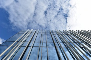 Düşük açı görünümlü bir gökdelen, mavi gökyüzüne karşı cam pencere cephesi