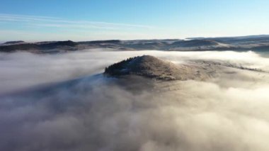 Gizemli sisli kış sabahında tepelerin üzerinden uçuyor. Havadan yavaş çekim görünümü