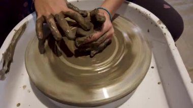 Çanak çömlek tekeri üzerinde çalışan bir çocuğun elleri kapalı.