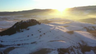 Sisli kış dağlarının üzerinden gün batımının havadan görünüşü