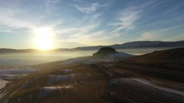 Sisli kış dağlarının üzerinden gün batımının havadan görünüşü