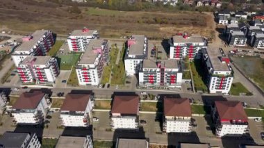  Çevresi yeşilliklerle çevrili çok sayıda apartman bloğu olan büyük bir yerleşim bölgesinin havadan görüntüsü.
