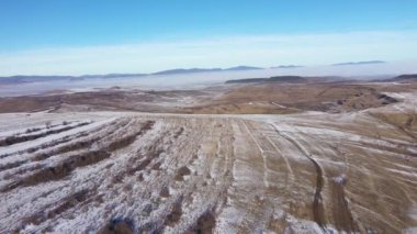  Güneşli, sisli bir günde, tepelerde eriyen karların insansız hava aracı görüntüsü.