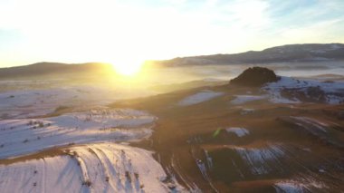 Sisli kış dağlarının üzerinden gün batımının havadan görünüşü