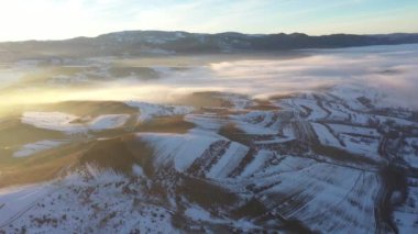 Sisli kış dağlarının üzerinden gün batımının havadan görünüşü