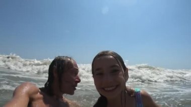 Yaz tatili boyunca baba ve kızının üzerine düşen deniz dalgalarının yavaş çekim görüntüsü