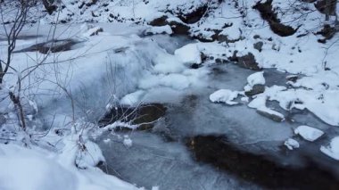 Kış mevsiminde aşırı soğuk havada dağ ormanlarında buzun altında akan su akıntısı