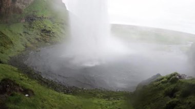Seljalandsfoss şelalesi bulutlu havada, İzlanda, su damlacıklarından ıslak kamera