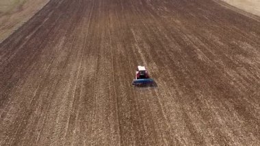 Tarım alanında tohum eken traktörün yavaş çekim görüntüsü. Toprak gevşiyor.