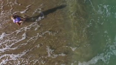  Kumsalda yürüyen muhteşem sarışın bir kadının yavaş çekim görüntüsü. Deniz dalgaları kumlu kıyı şeridini yıkıyor