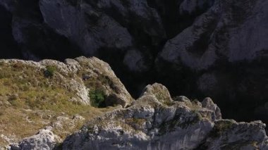 Derin bir vadide, kanyonda, kaya tırmanışı havasında dikey kireçtaşı duvarların içinden uçuyor. 