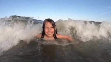 Yaz tatili boyunca deniz dalgalarının küçük kıza vuruşunu yavaş çekimde izlemek.