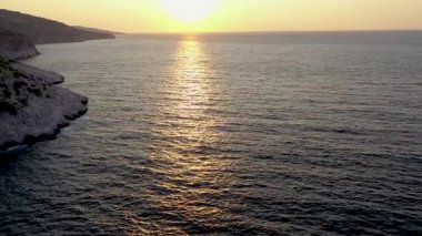 Yunanistan 'ın Thassos adasının kayalık kıyı şeridi yakınlarındaki güneşin doğuşu sırasında denizin yavaş çekim görüntüsü