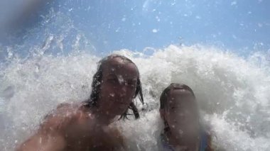 Yaz tatili boyunca baba ve kızının üzerine düşen deniz dalgalarının yavaş çekim görüntüsü