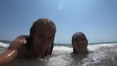 Yaz tatili boyunca baba ve kızının üzerine deniz dalgaları sıçrıyor.