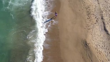   Kumsalda yürüyen muhteşem sarışın bir kadının yavaş çekim görüntüsü. Deniz dalgaları kumlu kıyı şeridini yıkıyor