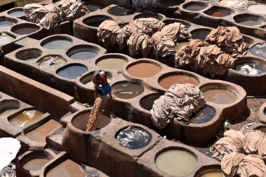 FEZ, MOROCCO - 31 Mayıs 2025: Chouara Tannery 'de deri döken işçiler, farklı renklerde boya ve beyaz sıvılarla dolu sayısız taş fıçı