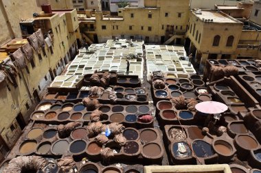 FEZ, MOROCCO - 31 Mayıs 2025: Chouara Tannery 'de deri döken işçiler, farklı renklerde boya ve beyaz sıvılarla dolu sayısız taş fıçı