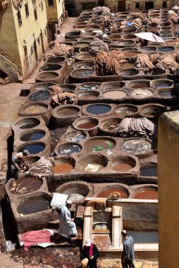 FEZ, MOROCCO - 31 Mayıs 2025: Chouara Tannery 'de deri döken işçiler, farklı renklerde boya ve beyaz sıvılarla dolu sayısız taş fıçı