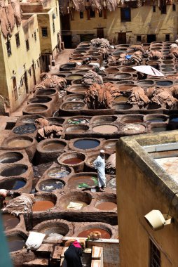 FEZ, MOROCCO - 31 Mayıs 2025: Chouara Tannery 'de deri döken işçiler, farklı renklerde boya ve beyaz sıvılarla dolu sayısız taş fıçı