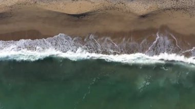 Gözlerden uzak bir sahil şeridini yıkayan okyanus dalgalarının havadan görünüşü
