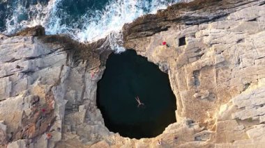  Giola 'nın doğal deniz havuzunda, gölde yüzen bir kadının baş döndürücü ve yavaş çekim görüntüsü. Thassos Adası, Yunanistan