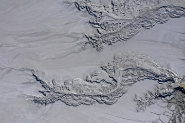 Gri, soyut çamur kalıpları ve asit madenindeki çatlakların havadan görüntüsü insansız hava aracıyla boşaltılıyor.