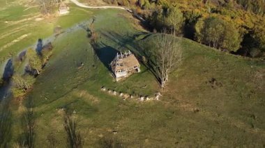 Sonbahar kırsalında, sazdan çatısı olan ücra dağ kulübesinde uçuyor. 