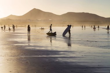 Famara sahilinde turistler ve sörfçüler, Caleta de Famara, Lanzarote, Kanarya Adaları, İspanya.