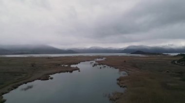 Yunanistan 'ın Makedonya kentindeki Prespa Gölü' nün nefes kesici güzelliğini bu büyüleyici panoramik hava aracı görüntüsüyle yaşayın. İnsansız hava aracı zarif bir şekilde güzel bir derenin üzerinde süzülüyor, nefes kesici bir teklif sunuyor.