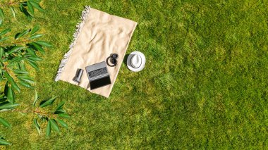 Laptop bilgisayar ve kulaklıklar park yeşil çim üzerinde, çevrimiçi açık havada çalışma, ofis konsepti dışında çalışma, yukarıdan hava üst görünümü