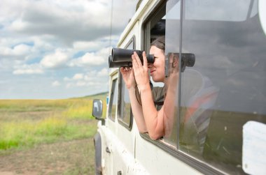 Afrika 'da safari yapan bir kadın, Kenya' da geziyor, vahşi hayatı dürbünle izliyor.