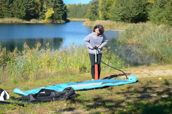 Active Woman Inflates Sup Board Manual Pump Beautiful Lake Nature 로열티 프리 스톡 이미지