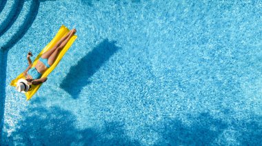 Beautiful woman in hat in swimming pool aerial drone view from above, young girl in bikini relaxes and swims on inflatable mattress and has fun in water on vacation, tropical holiday resort