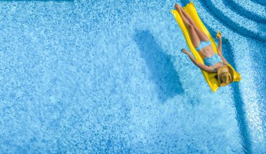 Yüzme havuzunda şapkalı güzel bir kadın yukarıdan drone manzaralı, bikinili genç bir kız şişme yatakta dinleniyor ve yüzüyor, genç kız tatilde suda eğleniyor, tropikal tatil beldesi.